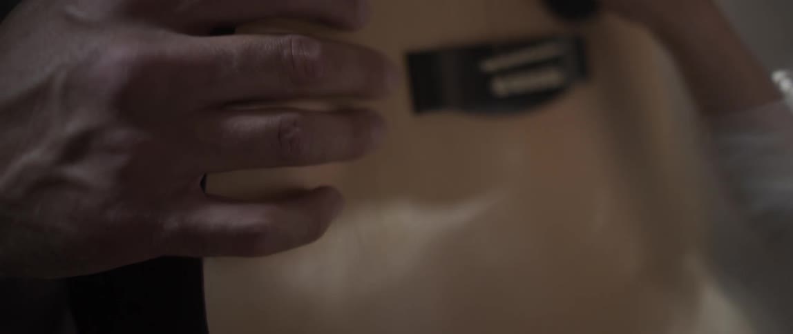 A boy runs his hand over the surface of a guitar