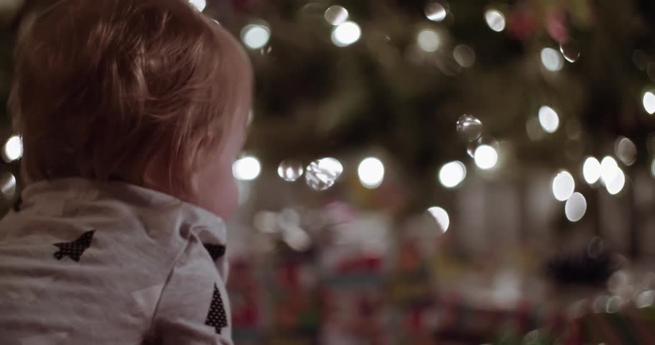 A baby crawls towards a christmas tree