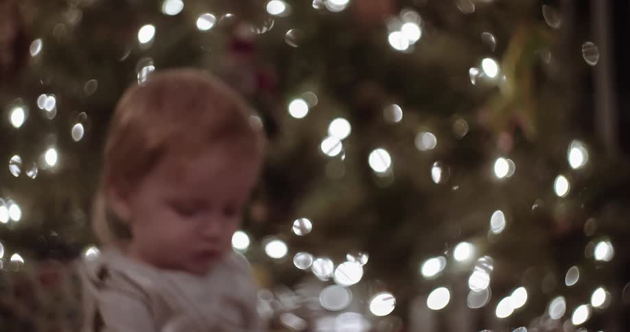 Infant sitting in front of a lighted christmas tree