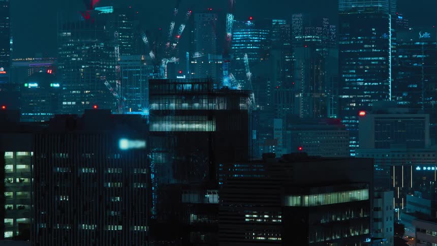 A skyscraper rises floor by floor with construction cranes and lights glowing at night