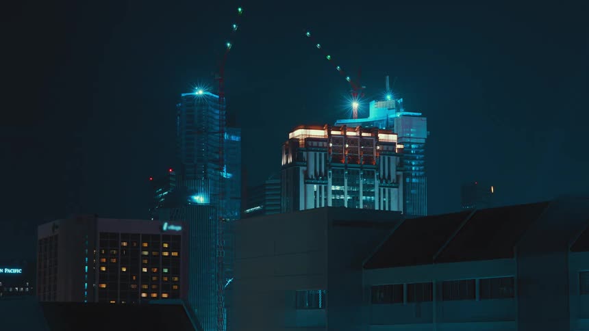 A city skyline with buildings and construction cranes with the sky in the background