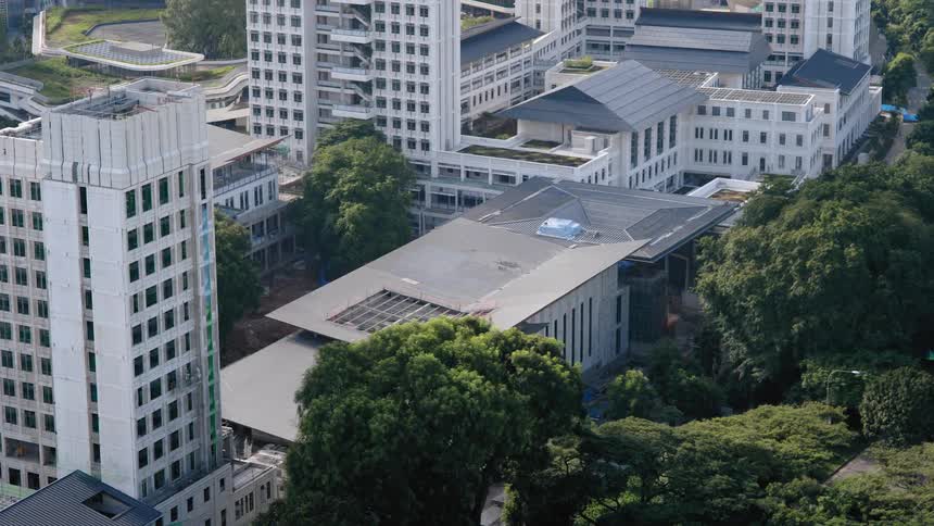 Construction crews finish work on a shorter wide building nestled between taller high rises