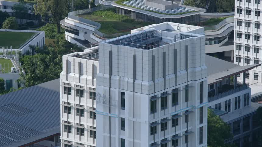 Construction crews complete a tall apartment building with a rooftop deck near a city trail