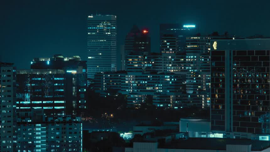 Colorful city lights shine through out downtown tower blocks including company name on building