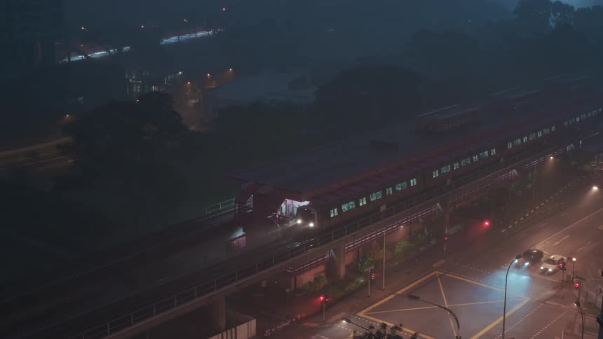 A train station with a train next to a street with vehicles and traffic lights
