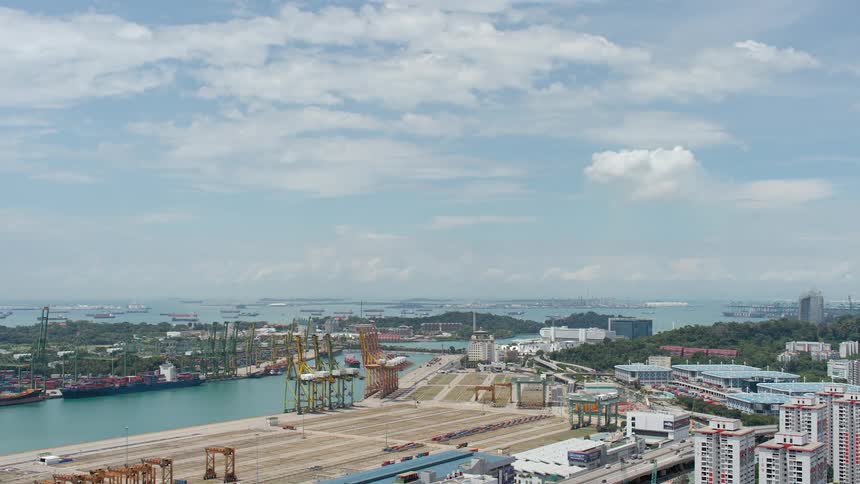 A shipyard with shipping containers and vehicles with the sky and clouds in the background