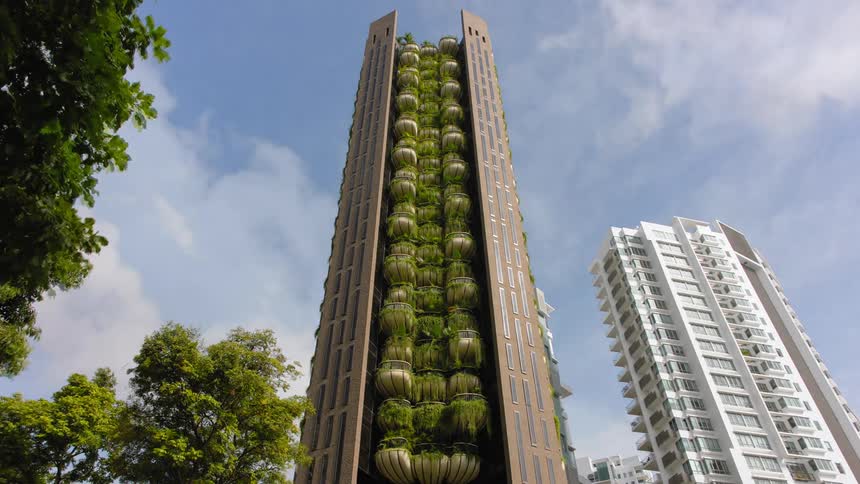 Lush plants fill the balconies on the side of a tall apartment building