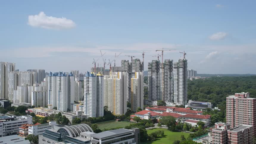 A city skyline with buildings and construction cranes with the sky in the background
