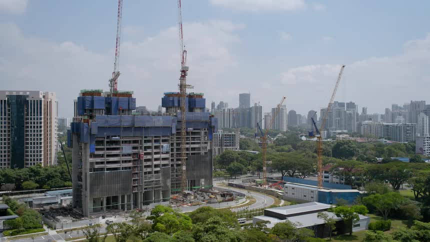 Construction crews use tall cranes while building a tall office building in a city