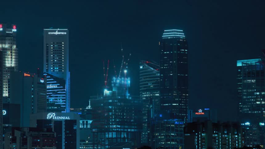 Construction crews work at night on a skyscraper in a dense city