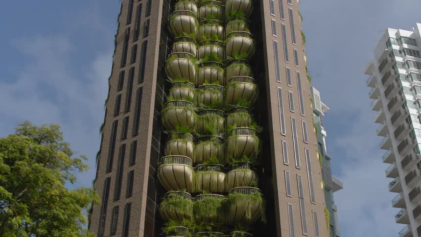 A building with balconies with plants with the sky and clouds in the background