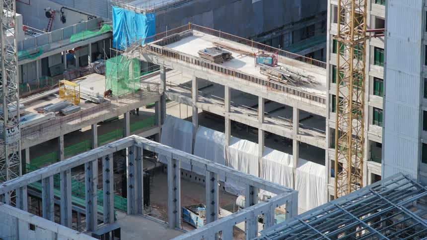 Construction crews add floors to an industrial building with green space on top