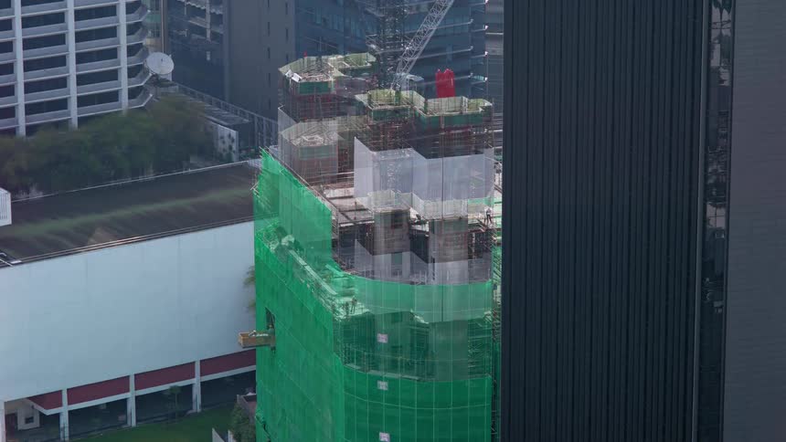 Green scaffolding surrounds a tall skyscraper under construction downtown