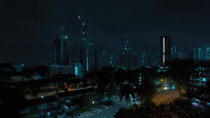 Construction cranes move as multiple buildings are built in city at night