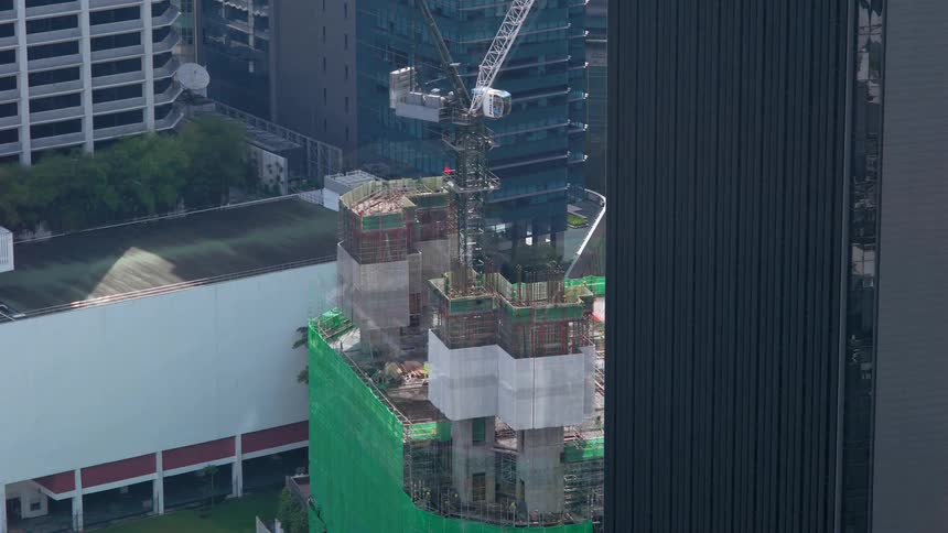 A city building goes up floor by floor with a construction crane and workers on top