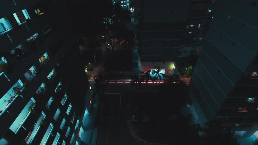 Time lapse of a car leaving a trail of light driving between buildings in the city at night