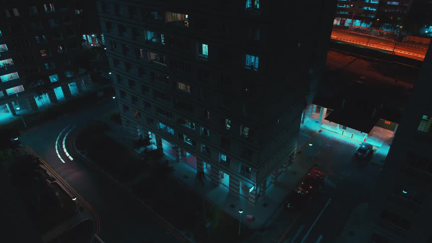 A time lapse shows some automobiles driving along city streets at night