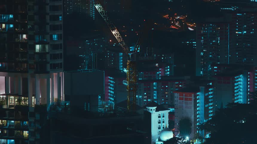 A construction crane on top of a skyscraper in a metropolis at night