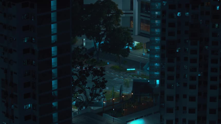 Car headlights and taillights create a red and white blur on a city street between buildings