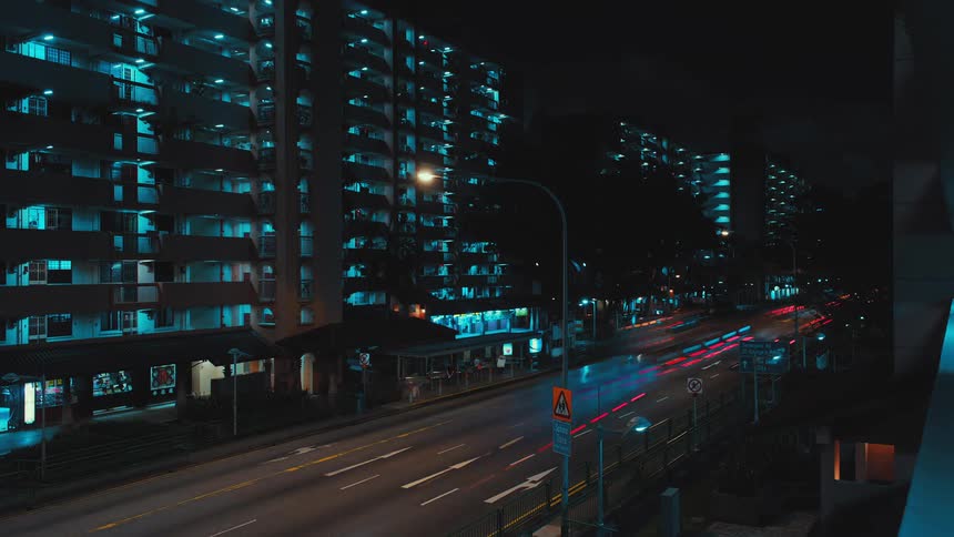 Traffic travels along a busy road in a metropolis at night