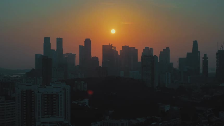 The sun begins to rise above a metropolitan city skyline filled with skyscrapers
