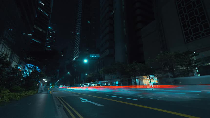 Numerous automobiles drive down a darkened city street in a surreal time lapse
