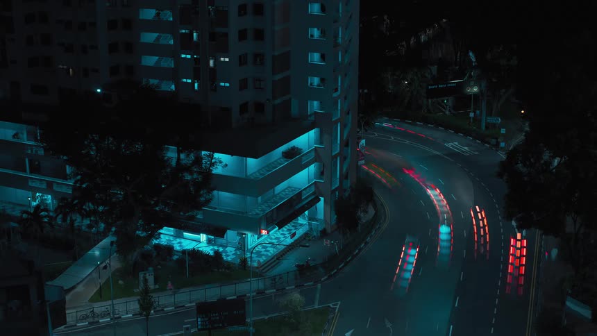 A time lapse shows numerous automobiles driving along a city street at night