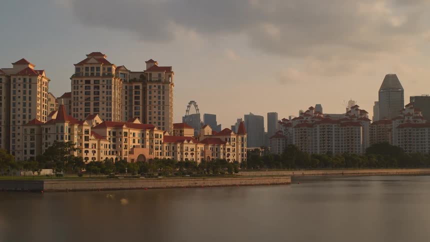 A city near a body of water with buildings and trees with the sky and clouds in the background
