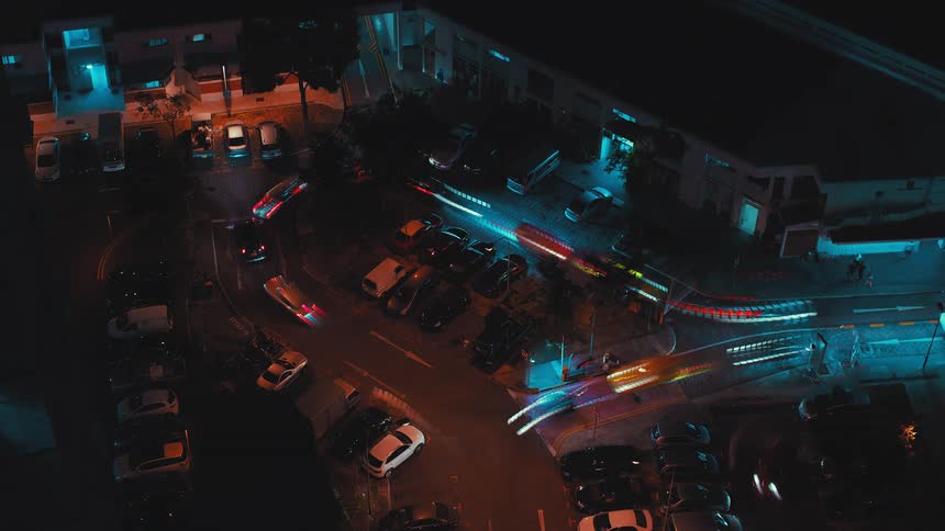 A time lapse shows numerous cars circling around a loop of city street at night