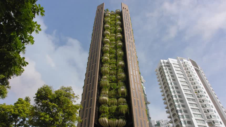 Plants line the balconies going straight down the side of a tall apartment