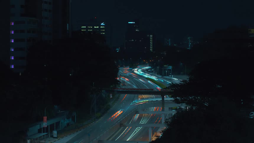 A time lapse shows numerous vehicles driving quickly along a city street at night