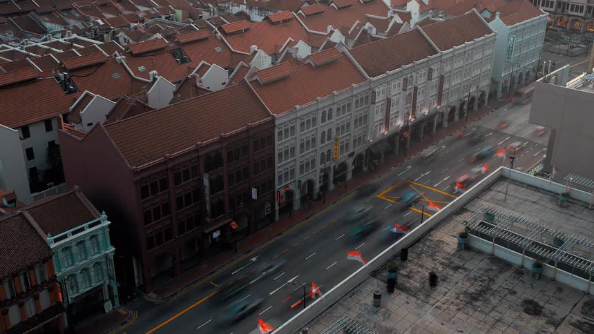 Vehicles flow down street between apartment buildings as night falls