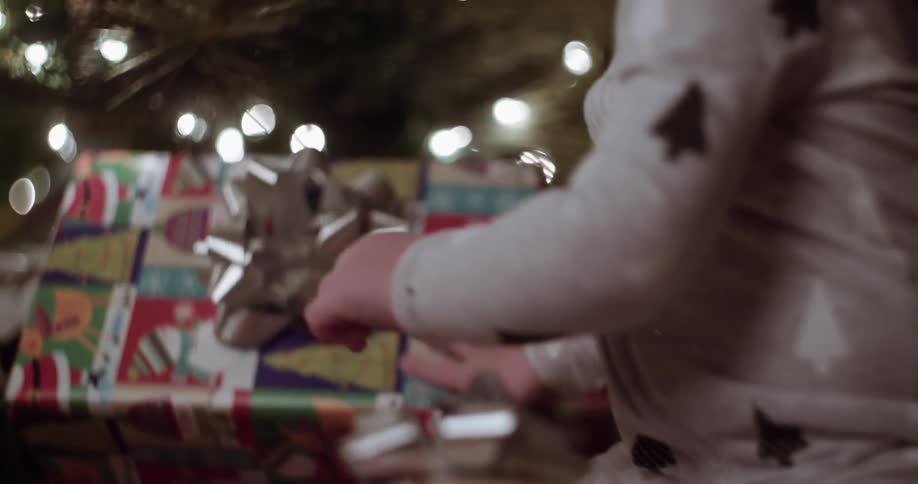 A child lifts presents from underneath a christmas tree