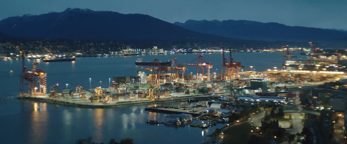 The port near the city is brightly lit at dusk