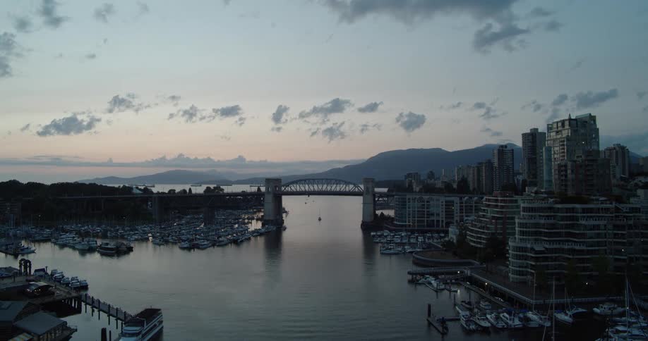 Time lapse of sun setting behind Vancouver's Burrard Bridge as boats move through the waterway