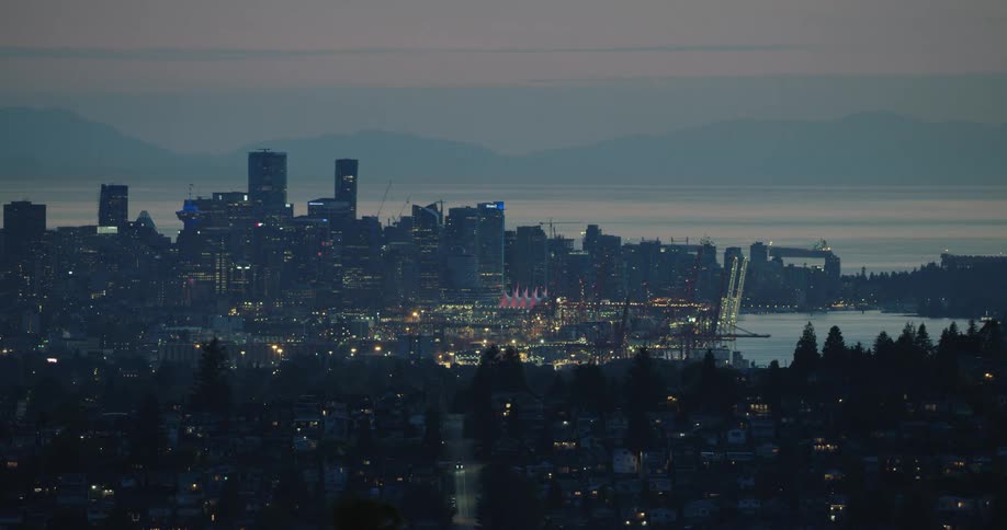 The silhouette of a large metropolitan city skyline is visible at dusk