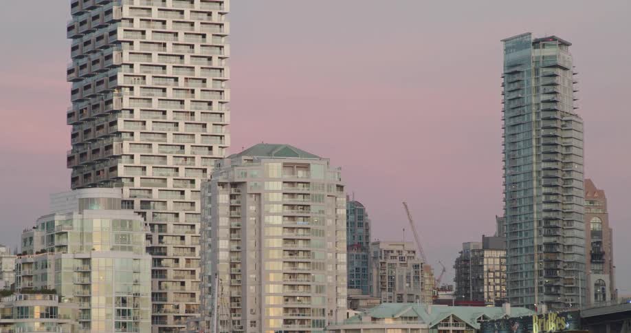 A Vancouver city skyline with glass buildings under the pink dusk sky