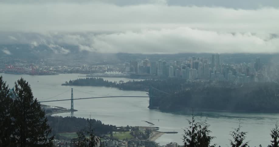 Clouds and fog move over Lion's Gate Bridge and coastal city skyline