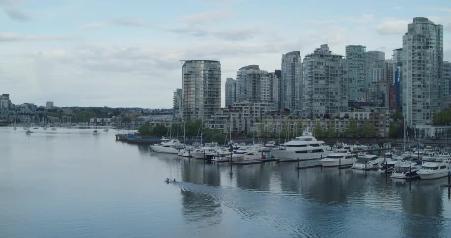 Tall buildings and apartments next to waterway with boats at dawn