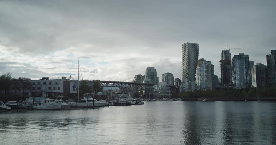 A large waterway passes next to a metropolitan area that is lined with glass skyscrapers