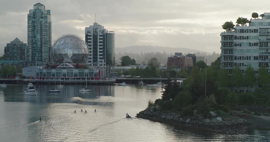A city waterway has four people kayaking in it at sunrise