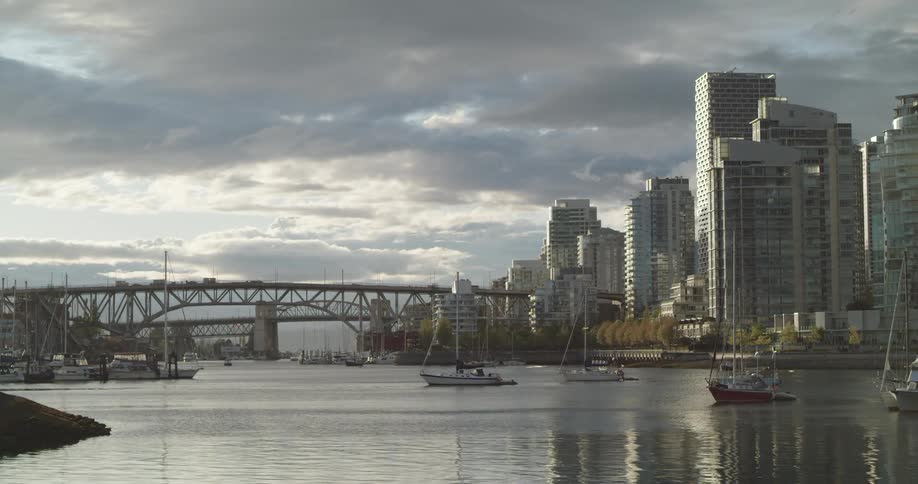 A view of a city skyline featuring two bridges and a waterway at sunset