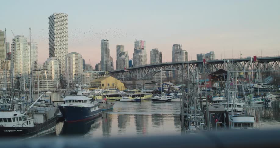 Boats sit idle in a marina located next to Granville Bridge leading to downtown Vancouver