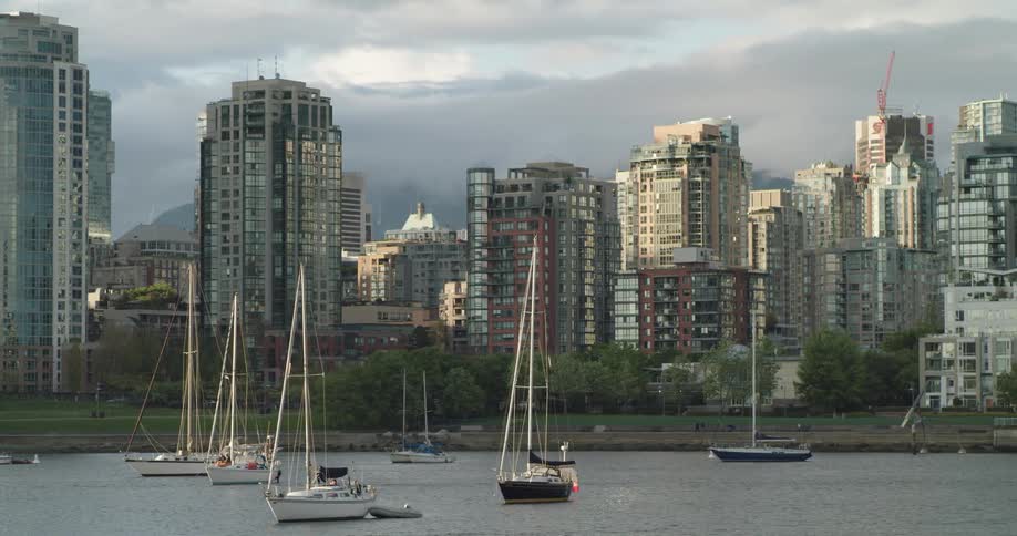 High rise buildings along sea wall next to ocean with boats and yachts