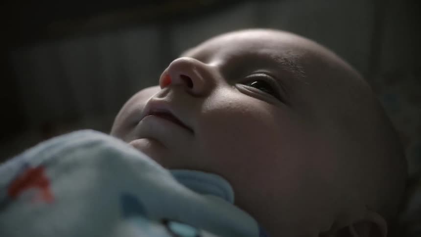 A baby looks upward while laying down