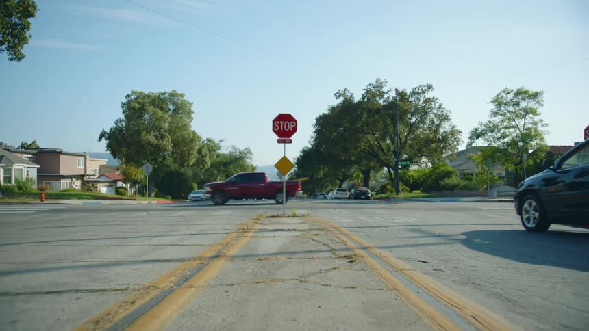 Various cars move through intersection near apartment buildings