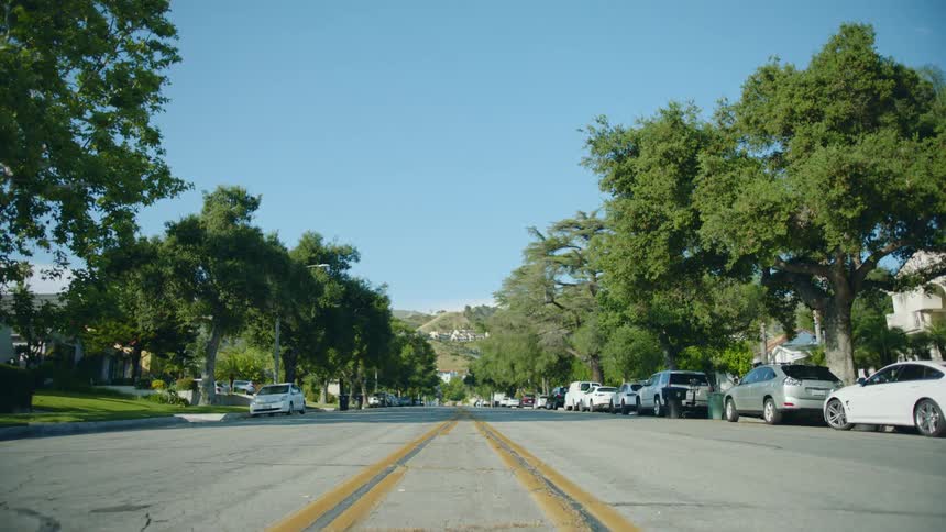 Numerous cars are parked along the sides of this residential neighborhood street