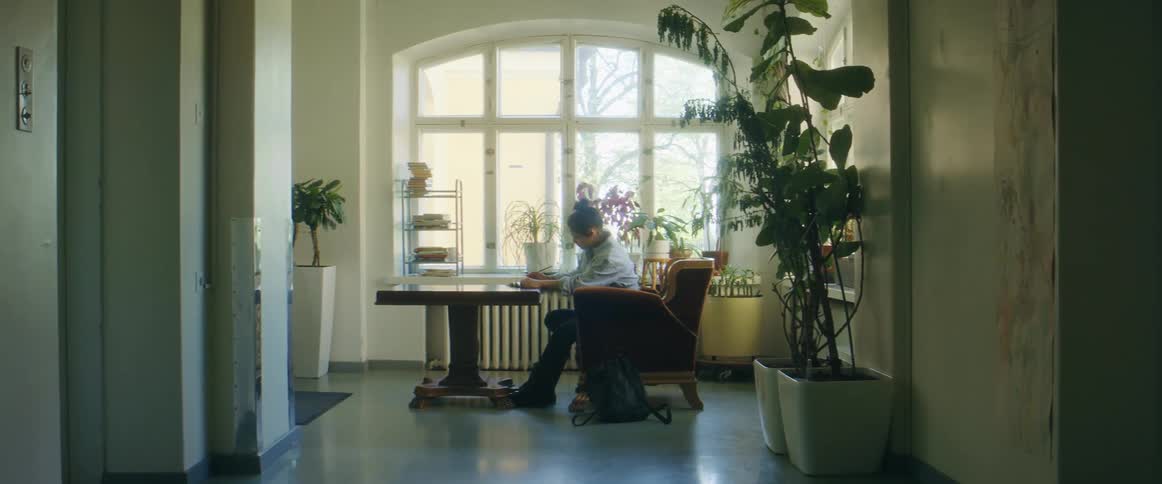 A person reads a book while sitting at a desk indoors during the day