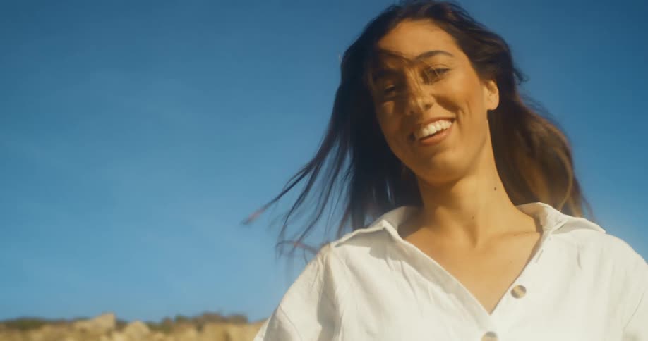 A woman smiles and plays with her hair as she twirls and walks