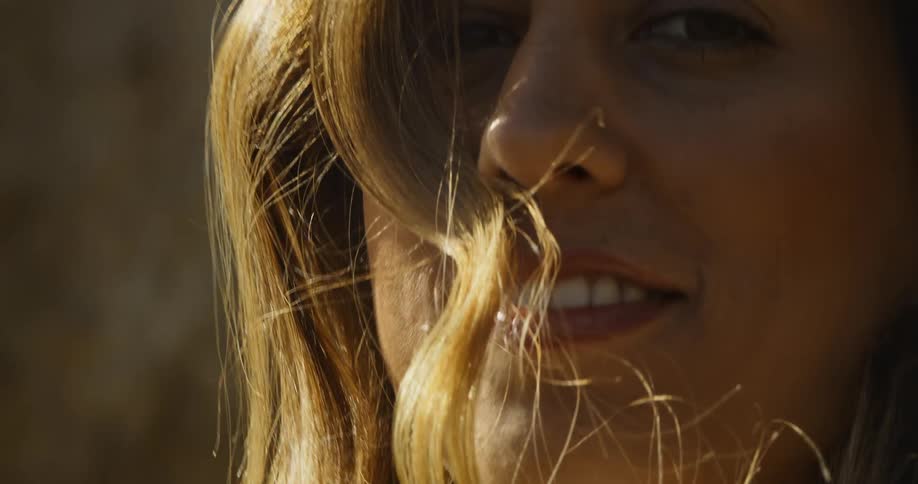 A woman smiles into the camera outdoors on a sunny day
